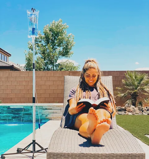 A woman reading by a desert pool while on an IV drip