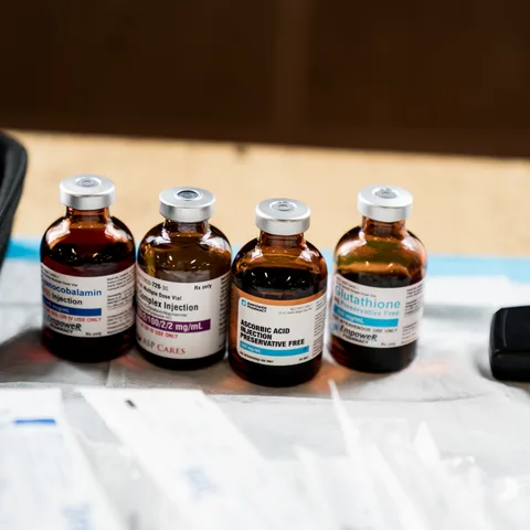 Amber add-in vials lined up on a table: B12, B-Complex, vitamin C and glutathione