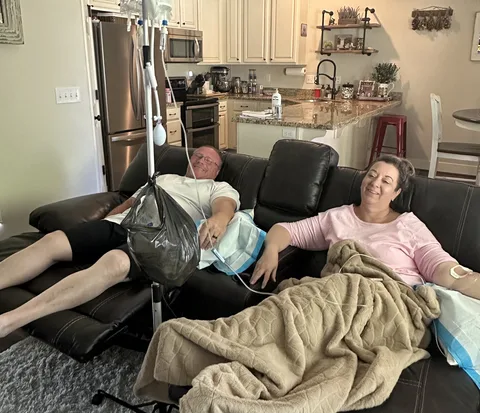Two people resting under blankets on their couches during their IVs