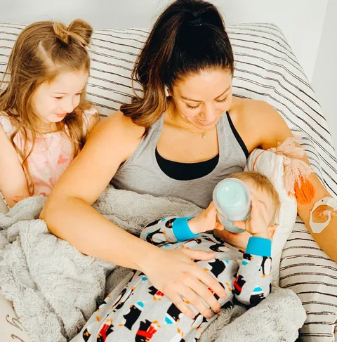 A mother feeding her baby with her toddler beside her during her IV