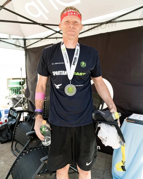 A Spartan race finisher with his medal at the DrpIV+ tent