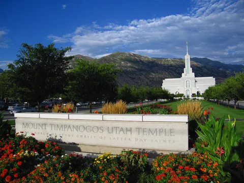 The Mount Timpanogos Utah Temple in American Fork, with flower beds in front and the Wasatch Mountains behind