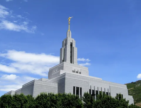 The Draper Utah Temple against a blue sky with white clouds