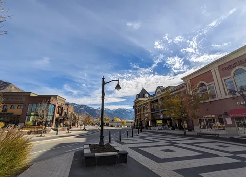 Holladay Village's brick shops and clock tower, with snowy Wasatch peaks behind