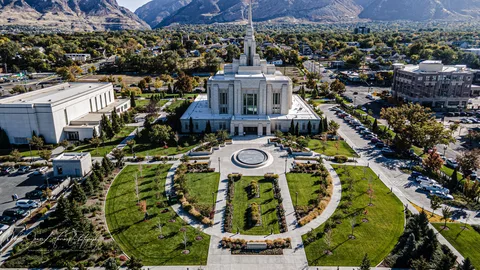 Aerial view of the Ogden Utah Temple and its gardens in autumn with the Wasatch Mountains behind