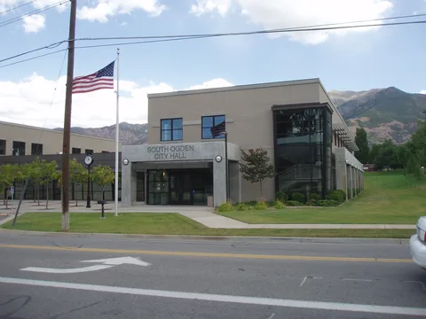 South Ogden City Hall with the American flag out front and the Wasatch Mountains behind