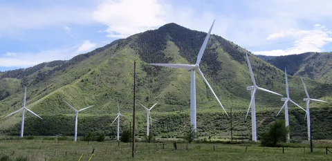 Wind turbines below a green mountain at the mouth of Spanish Fork Canyon