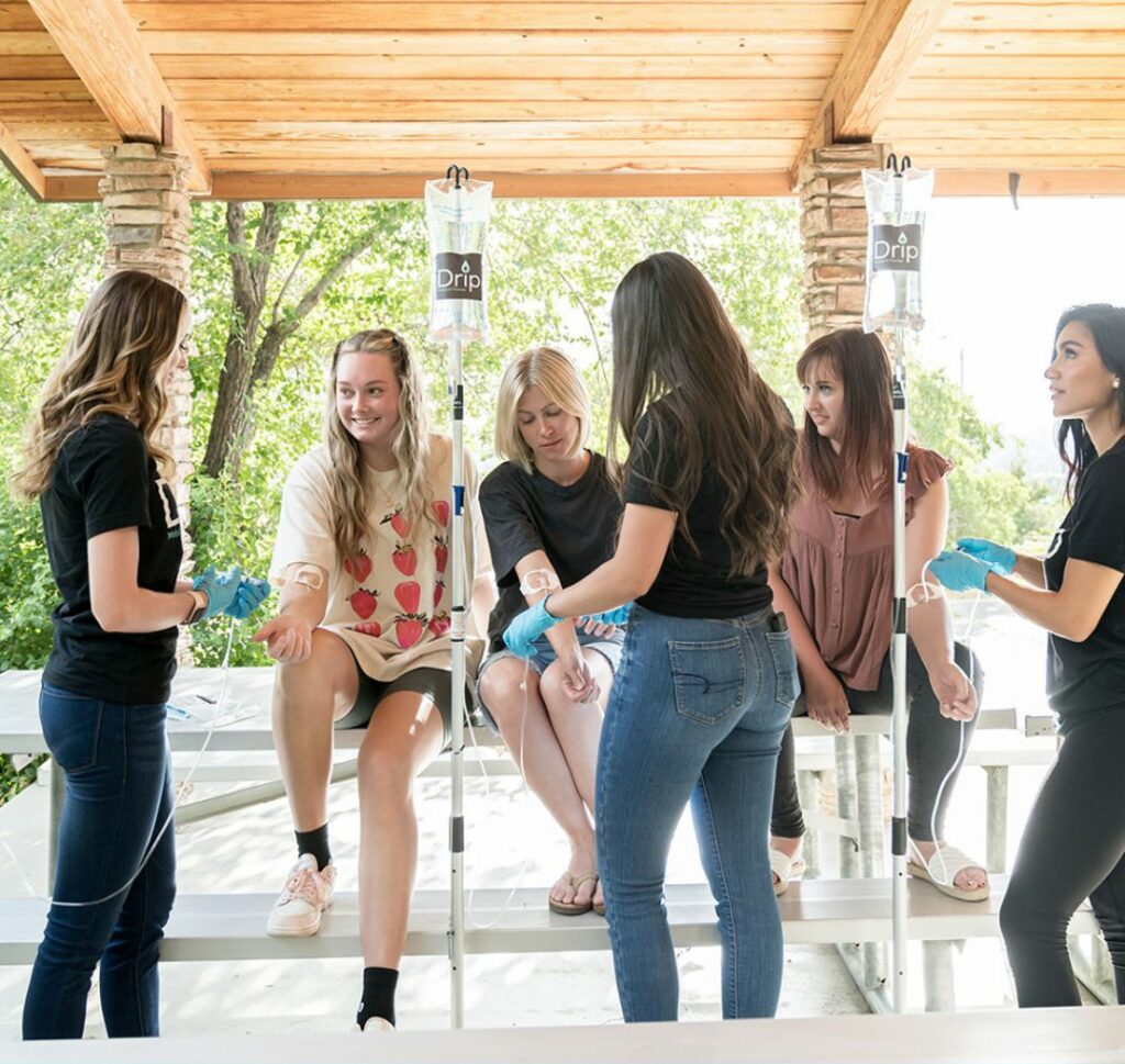 Three girls sitting on park table getting a beauty IV from nurses