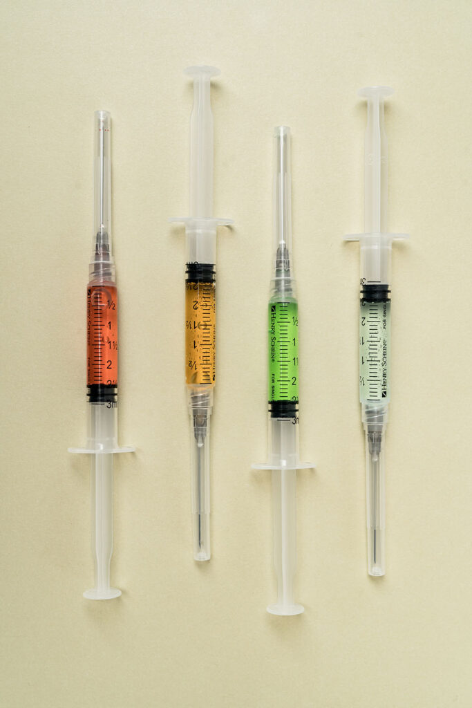 4 syringes full of different colored vitamins for post about how long does a toradol shot last