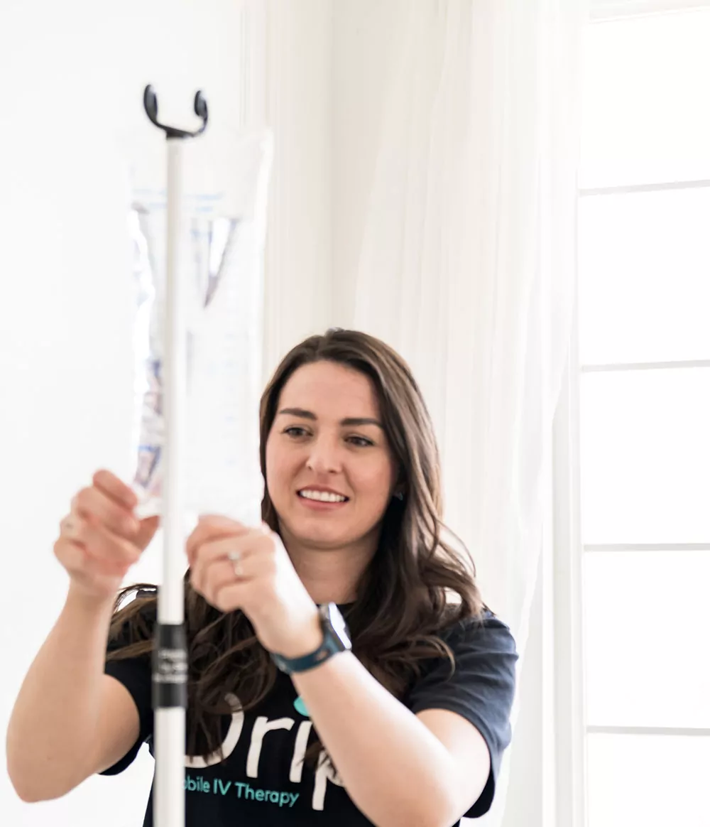 Smiling Nurse Sets Up IV Bag for iv therapy in centerville