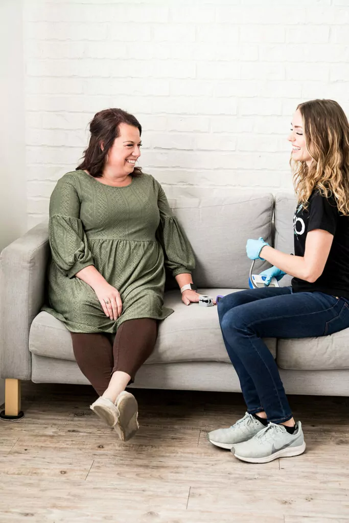 Two ladies on a couch. Nurse doing vitals for a woman about to get an IV for pregnancy