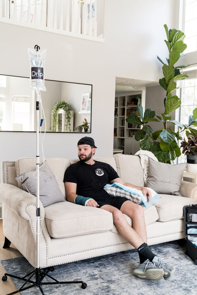 man sitting on couch getting a hydration IV treatment