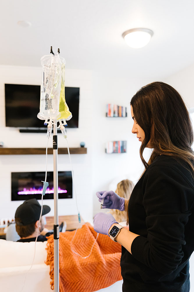 Nurse administering mobile IV therapy in Sandy standing next to two IV bags hanging on a pole