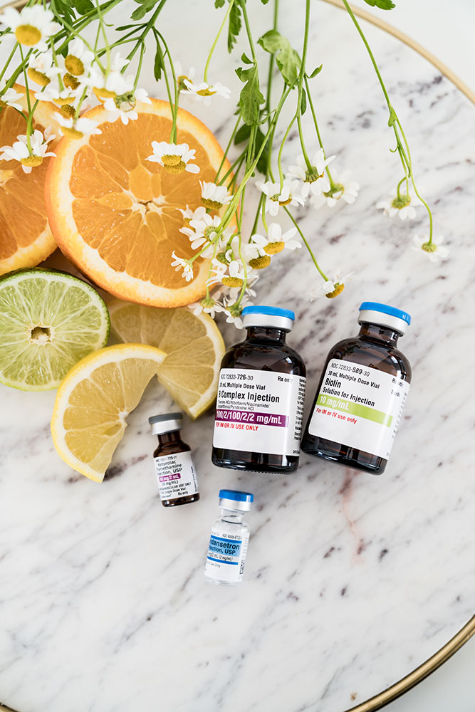 Vitamin B Complex shot Vial next to other vitamin vials with oranges, lemons, and limes to the left