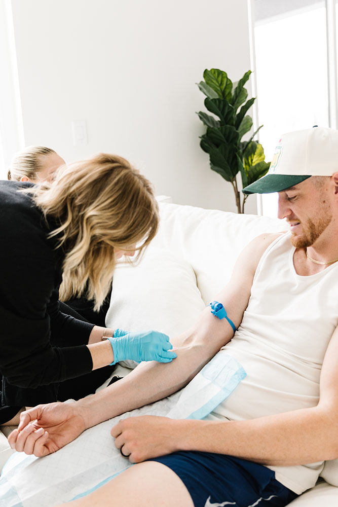 Mobile IV Therapy in cottonwood heights being administered to a man on a white couch. The nurse is expertly placing the IV in the forearm