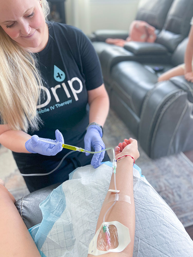 Nurse giving IV therapy in Eagle Mountain UT. Nurse pushing b-complex into the IV piping going into patient's arm