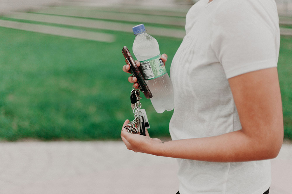 Woman with bottle wondering how many water bottles should I drink per day