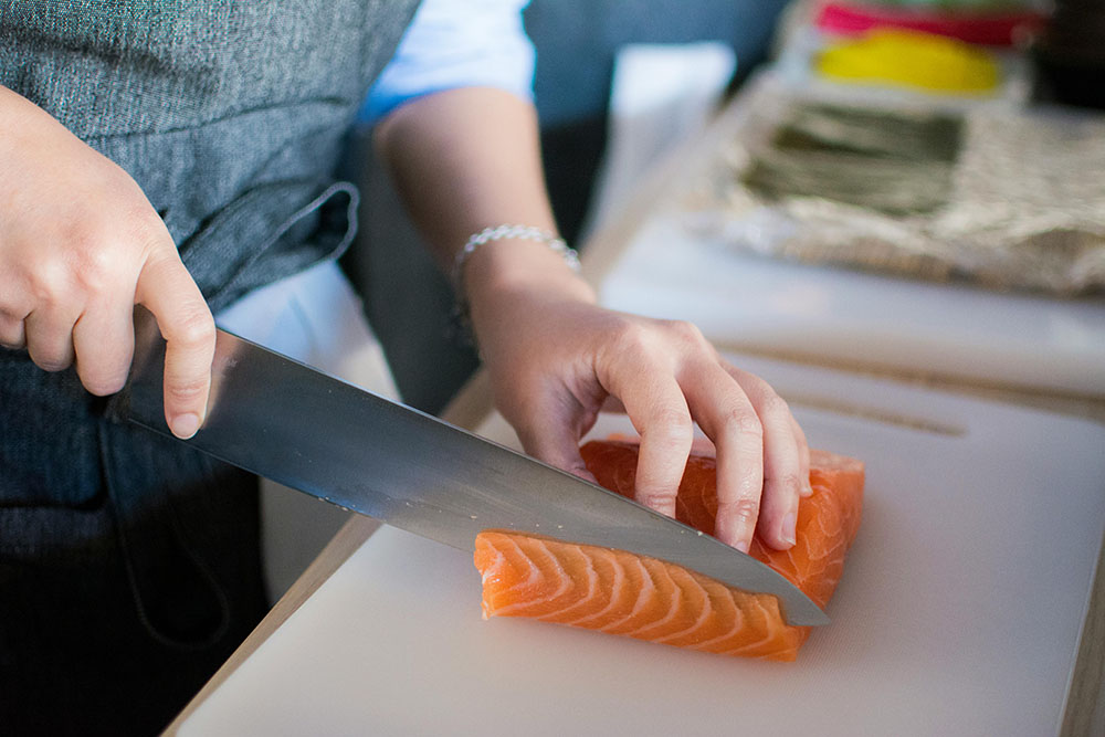 salmon is high on the list of what food has vitamin d3. This shows a chef thinly slicing a cut of salmon in preparation for sushi