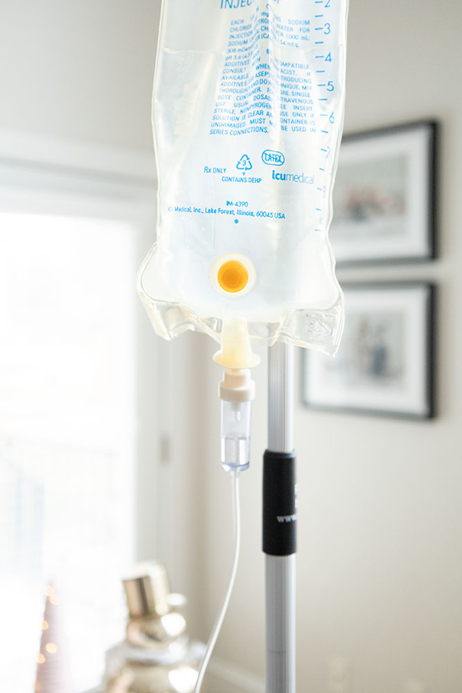 Saline bag providing the benefits of glutathione iv therapy to patients. Close up on iv bag with a home environment in the background