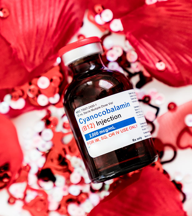 B12 Energy Shot Vial against a background with red rose petals and sequence