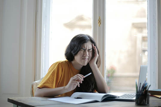 woman in yellow with a migraine who needs Toradol for migraines