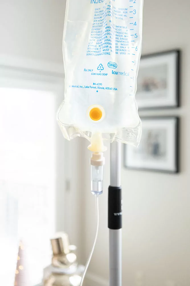 Saline bag providing the benefits of glutathione iv therapy to patients. Close up on iv bag with a home environment in the background